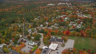 AX151_102 - 5.5K aerial stock footage flying by a small rural town with colorful foliage, autumn, New London, New Hampshire