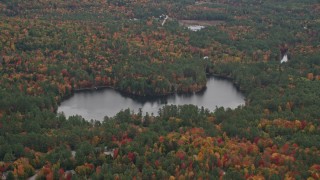 AX151_108 - 5.5K aerial stock footage flying by Chase Pond, waterfront homes, forest, autumn, Wilmot, New Hampshire