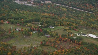 AX151_119E - 5.5K aerial stock footage flying by rural homes, grassy clearings, colorful trees, autumn, Warner, New Hampshire
