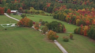 AX151_124 - 5.5K aerial stock footage flying by grassy clearings, red barn, colorful trees, autumn, Warner, New Hampshire