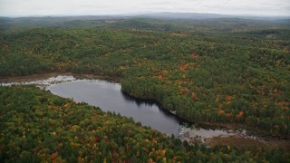 AX151_125E - 5.5K aerial stock footage flying over Trumbull Pond, forest in autumn, reveal Lake Winnepocket, Webster, New Hampshire