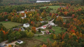 AX151_133E - 5.5K aerial stock footage orbiting a small town, church, colorful foliage in autumn, Webster, New Hampshire