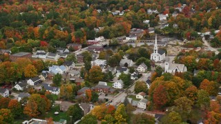 AX151_151E - 5.5K aerial stock footage orbiting church, colorful foliage, small town, autumn, Penacook, New Hampshire