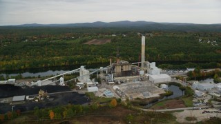 AX152_006 - 5.5K aerial stock footage flying by a power plant, colorful foliage in autumn, Bow, New Hampshire