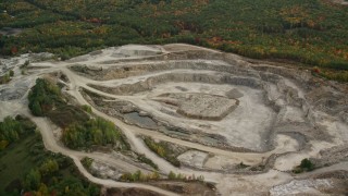 AX152_010E - 5.5K aerial stock footage flying over forest, approaching a quarry, pan right, autumn, Bow, New Hampshire