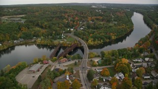 AX152_015E - 5.5K aerial stock footage orbiting small town, homes, small bridges, Merrimack River, autumn, Hooksett, New Hampshire