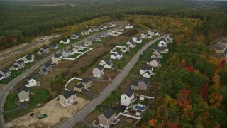AX152_020 - 5.5K aerial stock footage flying by tract homes, colorful foliage in autumn, Hooksett, New Hampshire
