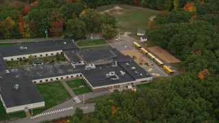 AX152_026E - 5.5K aerial stock footage orbiting Hooksett Memorial School, revealing buses, autumn, Hooksett, New Hampshire