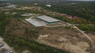 AX152_029E - 5.5K aerial stock footage over quarry, approach warehouse building, autumn, Hooksett, New Hampshire