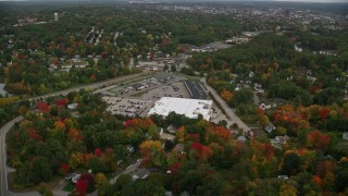 AX152_035 - 5.5K aerial stock footage flying over colorful foliage, approaching a store, tilt down, autumn, Manchester, New Hampshire