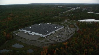 AX152_051 - 5.5K aerial stock footage flying by warehouse building, forest in autumn, Londonderry, New Hampshire