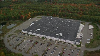 AX152_051E - 5.5K aerial stock footage flying by warehouse building, forest in autumn, Londonderry, New Hampshire