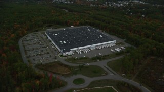 AX152_052 - 5.5K aerial stock footage flying away from a warehouse building, dense forest, autumn, Londonderry, New Hampshire