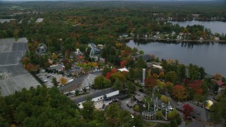 AX152_077 - 5.5K aerial stock footage orbiting colorful trees, attractions, Canobie Lake Park, autumn, Salem, New Hampshire