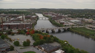AX152_088E - 5.5K aerial stock footage flying by factories, smoke stacks, reveal and fly over small bridges, Merrimack River, autumn, Lawrence, Massachusetts