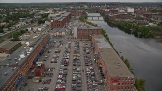 AX152_091E - 5.5K aerial stock footage orbit riverfront factories, smoke stacks, approach bridges and river in autumn, overcast, Lawrence, Massachusetts