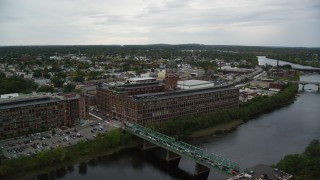 AX152_102 - 5.5K aerial stock footage of a factory and clock tower by the water, overcast, Lawrence, Massachusetts
