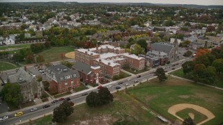 AX152_107E - 5.5K aerial stock footage approaching a park and high school among partial fall foliage, Lawrence, Massachusetts