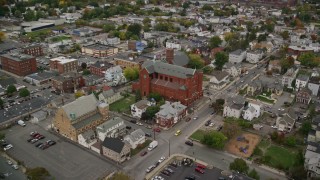 AX152_112 - 5.5K aerial stock footage flying over church in a town with partial fall foliage, autumn, Lawrence, Massachusetts