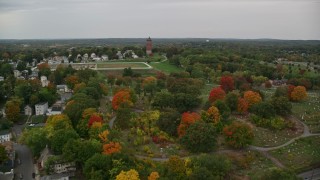 AX152_113E - 5.5K aerial stock footage flying over fall trees toward a cemetery and water tower, autumn, Lawrence, Massachusetts