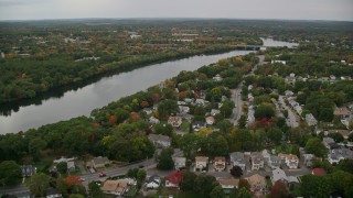 AX152_117 - 5.5K aerial stock footage flying over town among fall foliage toward a river, autumn, Methuen, Massachusetts