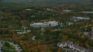 AX152_118 - 5.5K aerial stock footage passing by an office building among fall foliage, autumn, Andover, Massachusetts