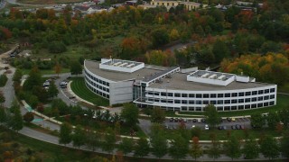 AX152_119 - 5.5K aerial stock footage approaching an office building and trees with fall foliage, Andover, Massachusetts
