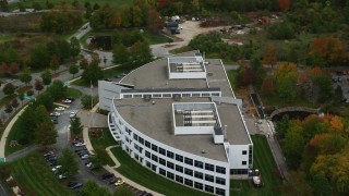 AX152_120 - 5.5K aerial stock footage orbiting away from an office building and fall trees, Andover, Massachusetts