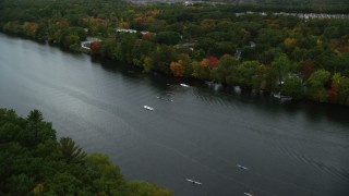 AX152_122 - 5.5K aerial stock footage flying over kayakers and rowers in a river lined with partial fall foliage, Andover, Massachusetts