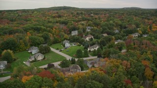 AX152_123 - 5.5K aerial stock footage flying by upscale homes among trees with fall foliage, Andover, Massachusetts