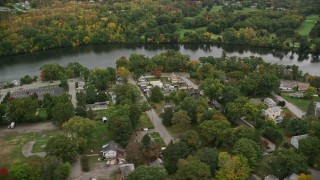 AX152_124E - 5.5K aerial stock footage of waterfront homes and businesses along the river and autumn trees, Dracut, Massachusetts