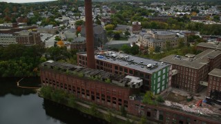 AX152_130 - 5.5K aerial stock footage tilting down on abandoned factory and smoke stack, Lowell, Massachusetts