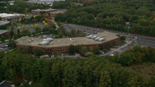 AX152_149 - 5.5K aerial stock footage approaching and orbiting away from office building and partial fall foliage, Chelmsford, Massachusetts