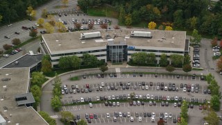 AX152_150E - 5.5K aerial stock footage tilting down on office building and parking lot among fall foliage, Chelmsford, Massachusetts
