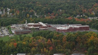 AX152_152 - 5.5K aerial stock footage approaching a prison surrounded by partial fall foliage, autumn, Billerica, Massachusetts
