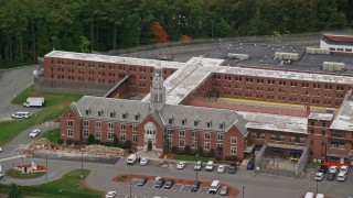 AX152_153 - 5.5K stock footage aerial video off a close up approach to a prison surrounded by trees, autumn, Billerica, Massachusetts