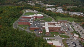 AX152_154E - 5.5K aerial stock footage orbiting away from a prison among trees, autumn, Billerica, Massachusetts