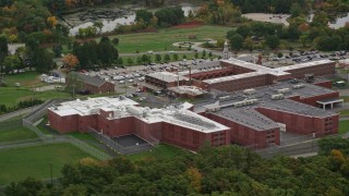 AX152_157 - 5.5K aerial stock footage of  side view orbiting a prison surrounded by trees, autumn, Billerica, Massachusetts