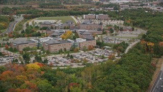 AX152_165 - 5.5K aerial stock footage flying by parking lots and office buildings among fall foliage, Burlington, Massachusetts