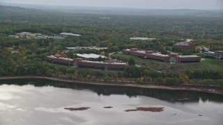 AX152_174 - 5.5K aerial stock footage flying by office buildings, colorful foliage on waterfront, autumn, Waltham, Massachusetts