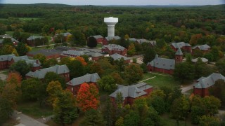 AX152_194 - 5.5K aerial stock footage of a side view of Medfield State Hospital and water tower among fall foliage, Medfield, Massachusetts