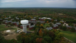 AX152_198 - 5.5K aerial stock footage flying by water tower and Medfield State Hospital among fall foliage, Medfield, Massachusetts