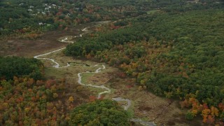 AX152_208E - 5.5K aerial stock footage flying over fall foliage and windy river, Medfield, Massachusetts