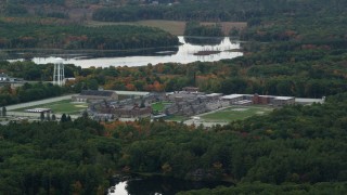 AX152_210 - 5.5K aerial stock footage of a slow approach over fall foliage toward Massachusetts Correctional Institution at Norfolk, Massachusetts