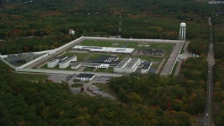 AX152_216 - 5.5K stock footage aerial video flying away from Massachusetts Correctional Institution Cedar Junction and fall trees, autumn, Walpole, Massachusetts