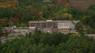 AX152_219 - 5.5K stock footage aerial video flying over fall foliage toward abandoned hospital, Walpole, Massachusetts