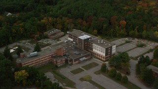 AX152_220 - 5.5K aerial stock footage orbiting away from an abandoned hospital among fall foliage, Walpole, Massachusetts