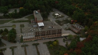 AX152_221 - 5.5K aerial stock footage orbiting away from an abandoned hospital surrounded by fall foliage, Walpole, Massachusetts