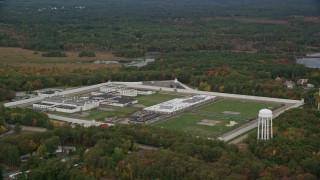AX152_222E - 5.5K aerial stock footage flying over trees with fall foliage along the Massachusetts Correctional Institution Cedar Junction, Walpole, Massachusetts