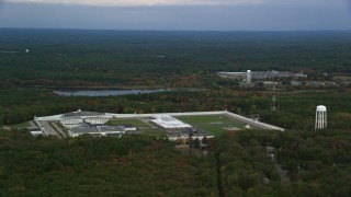 AX152_223 - 5.5K stock footage aerial video of a high view passing by Massachusetts Correctional Institution Cedar Junction among fall foliage, Walpole, Massachusetts